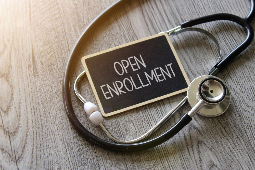 Stethoscope,and,chalkboard,with,text,open,enrollment,on,wooden,table.
