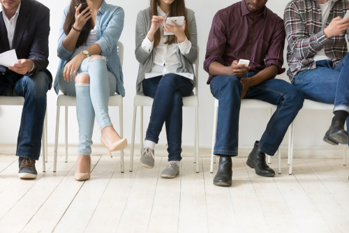 Diverse,black,and,white,people,sitting,in,row,using,smartphones