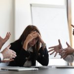 Frustrated,millennial,female,worker,sitting,at,table,with,colleagues,,felling